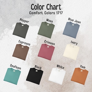 May include: A color chart for Comfort Colors 1717 t-shirts displaying nine folded shirts in various colors labeled Pepper, Moss, Blue Jean, Espresso, Crimson, Ivory, Seafoam, Black, White, and Yam, arranged in a grid on a textured background.
