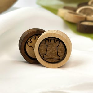 Può includere: Due pezzi di gioco in legno con un design a torre. Un pezzo è di colore marrone chiaro con una torre marrone scuro, e l'altro pezzo è marrone scuro con una torre marrone chiaro.