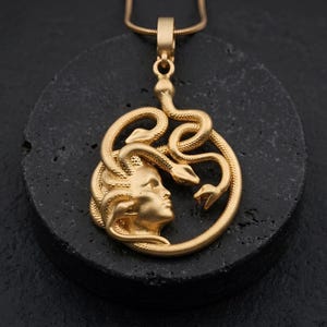 Handmade 18K gold plated Medusa necklace featuring a circular pendant with a detailed relief of Medusa's head and serpents. Available in matte gold, shiny gold, and antique silver finishes. Ancient Greek mythology jewelry, protective snake pendant, unique spiritual gift for her, versatile mythological necklace for everyday wear.