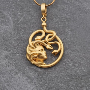 Handmade 18K gold plated Medusa necklace featuring a circular pendant with a detailed relief of Medusa's head and serpents. Available in matte gold, shiny gold, and antique silver finishes. Ancient Greek mythology jewelry, protective snake pendant, unique spiritual gift for her, versatile mythological necklace for everyday wear.