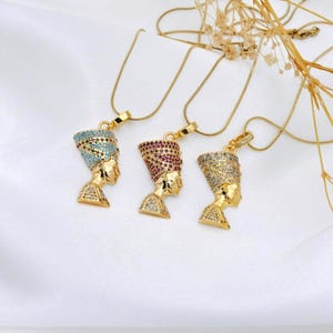 Handmade 24K gold plated Nefertiti necklaces shown in three vibrant gemstone colors including turquoise fuchsia and clear. This collection of Egyptian queen jewelry for women serves as a stunning anniversary gift for her or a high quality spiritual gift for mom designed for daily elegance.