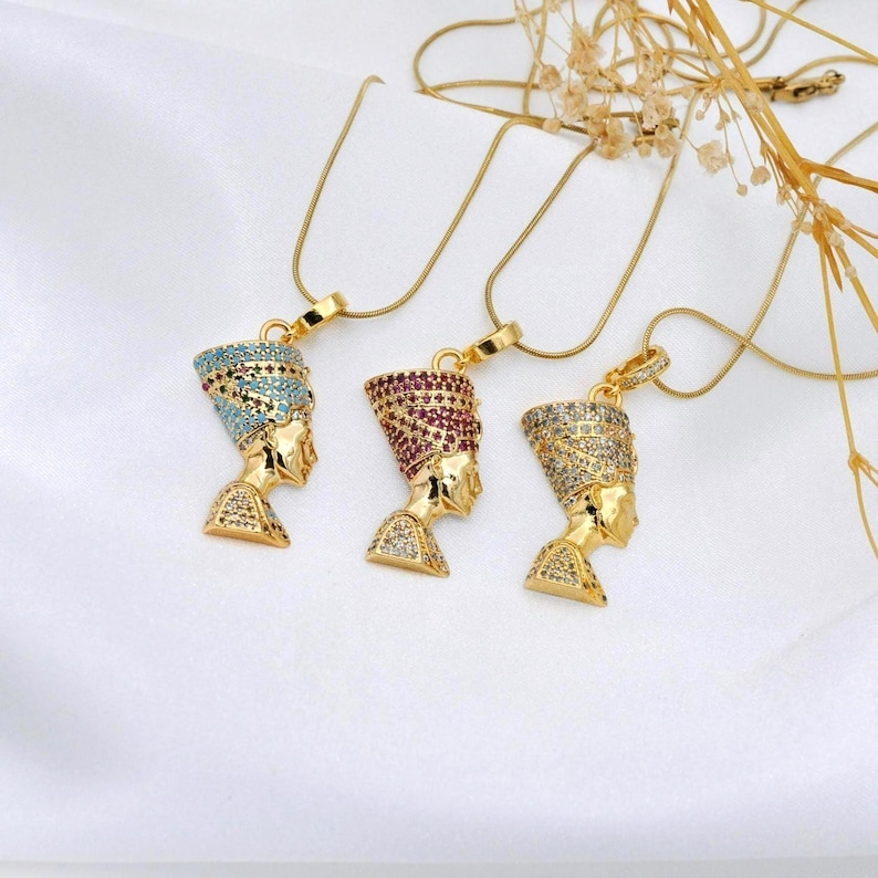 Handmade 24K gold plated Nefertiti necklaces shown in three vibrant gemstone colors including turquoise fuchsia and clear. This collection of Egyptian queen jewelry for women serves as a stunning anniversary gift for her or a high quality spiritual gift for mom designed for daily elegance.