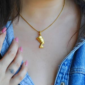 A female model wearing the 24K gold plated Nefertiti necklace to show the perfect scale and fit. This elegant necklace for women is a popular choice for anniversary gifts for her or a birthday gift for mom. The Egyptian queen necklace sits beautifully on the chest, making it a versatile gift for her.