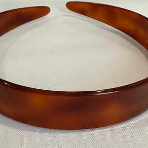 May include: A brown plastic headband with a tortoise shell pattern.