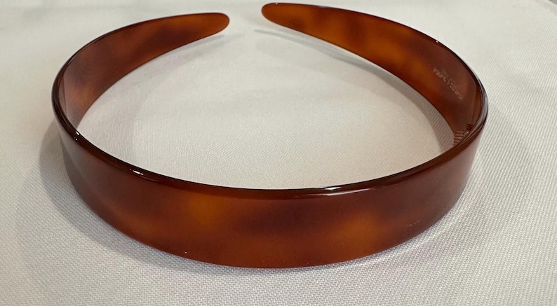 May include: A brown plastic headband with a tortoise shell pattern.