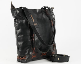 Puede incluir: Bolso tote de cuero negro con detalles de costuras marrones y una correa de hombro desmontable. El bolso presenta el nombre de la marca "MORABEL" y una pequeña etiqueta. Está diseñado con un interior espacioso y un estilo clásico y versátil.