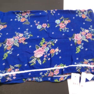 May include: A blue scarf with a white border and a floral print. The flowers are pink, white, and yellow.