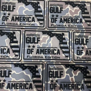May include: Five black and white patches with a camouflage background. Each patch features a silhouette of the state of Florida with an American flag design. The text "GULF OF AMERICA FLORIDA EDITION" is printed on each patch.