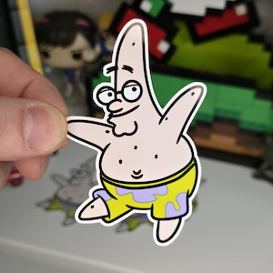 May include: A sticker of Patrick Star from Spongebob Squarepants. The sticker features Patrick in his yellow shorts with purple accents, a yellow waistband, and a white outline. Patrick is wearing glasses and has a smiling expression.