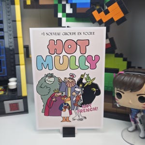 May include: A rectangular print featuring the words "HOT MULLY" in colorful bubble letters, with the text "#1 NOUVEAU GROUPE EN VOGUE" above and "NOT FRENCH!" below. The print showcases cartoon characters in various outfits.