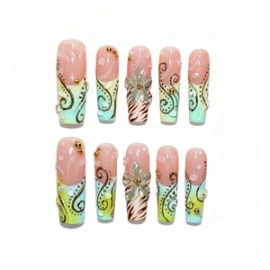May include: A set of ten press-on nails featuring a gradient from nude to light green. The design includes raised 3D floral accents, gold metallic swirls, small gold beads, and white pearls. Two nails feature a brown and white zebra-like pattern.
