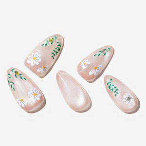 以下が含まれることがあります： ライトピンクのパール仕上げの人工爪5本。各爪には、黄色の中心と緑の葉が付いた白いデイジーのデザインが施されています。1つの爪は無地です。小さな金の宝石がいくつかの爪に付いています。