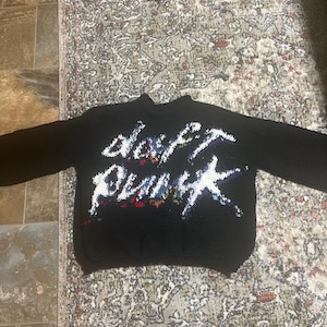 Pode incluir: Camisola de malha preta com uma estampa gráfica colorida das palavras "Happy Punk" em branco e arco-íris.
