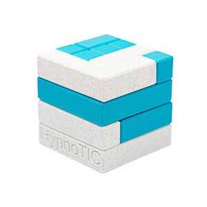 Op de afbeelding: Een kubusvormige puzzel met een witte gespikkelde afwerking en turquoise accenten. De puzzel bestaat uit in elkaar grijpende rechthoekige blokken. De tekst "HypnoTIC" is op één kant gedrukt. Een hersenkraker of een leuk spel.