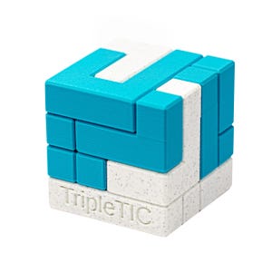 Op de afbeelding: Een driedimensionale puzzelkubus in wit, gespikkeld en turquoise. De kubus bestaat uit in elkaar grijpende stukken, met de tekst "Triple TIC" op één kant. De puzzel is ontworpen om het ruimtelijk inzicht uit te dagen.