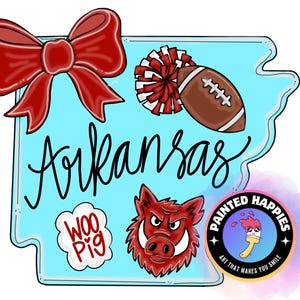 May include: A light blue outline of the state of Arkansas with the word "Arkansas" in black script. The design includes a red bow, a football, a pom-pom, a "Woo Pig" speech bubble, and a red Razorback mascot. A "Painted Happies" logo is in the bottom right.