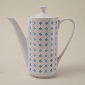 May include: A white ceramic coffee pot with a lid, spout, and handle. The pot is decorated with a repeating pattern of blue and grey diamonds. A classic design for serving coffee.