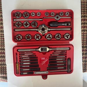 Puede incluir: Una caja de herramientas roja que contiene un juego de machos de roscar y terrajas. El juego incluye machos de roscar, terrajas y herramientas relacionadas de varios tamaños, ordenadas cuidadosamente dentro de la caja. La caja de herramientas está etiquetada como "Super Set".