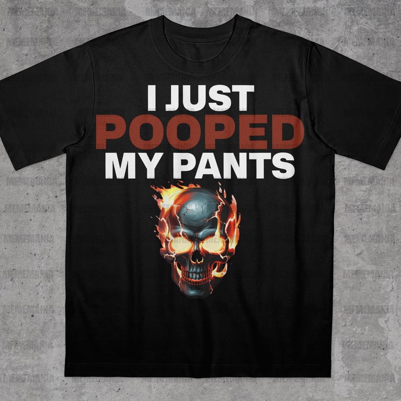 Peut inclure: T-shirt noir avec l'inscription "I JUST POOPED MY PANTS" en blanc et rouge. Un cr&acirc;ne en flammes avec des yeux jaunes est plac&eacute; sous le texte. Le cr&acirc;ne est entour&eacute; de flammes orange.