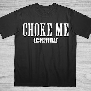 以下が含まれることがあります： 「CHOKE ME」と「RESPECTFULLY」の白い文字がプリントされた黒いTシャツ。Tシャツは半袖で、クルーネックです。テキストは太字のサンセリフ体です。