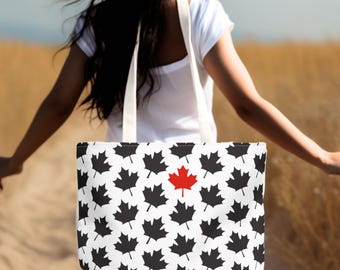 May include: A white tote bag with a black and white pattern of maple leaves. One of the leaves is red.