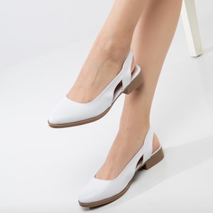 May include: White leather slingback shoes with a pointed toe and a low heel. The shoes have a cut-out design on the back strap.