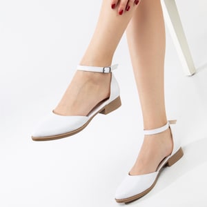 Op de afbeelding: Witte enkelband sandalen met een spitse neus en een lage blokhak.