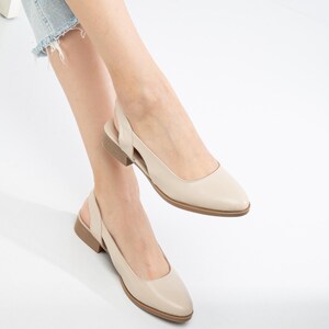 May include: A pair of beige leather slingback shoes with a pointed toe and a low heel.