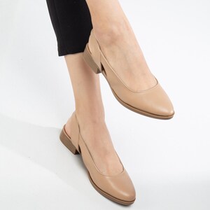 May include: A pair of beige leather slingback shoes with a pointed toe and a low heel.
