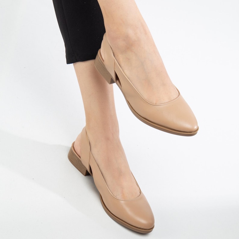 May include: A pair of beige leather slingback shoes with a pointed toe and a low heel.