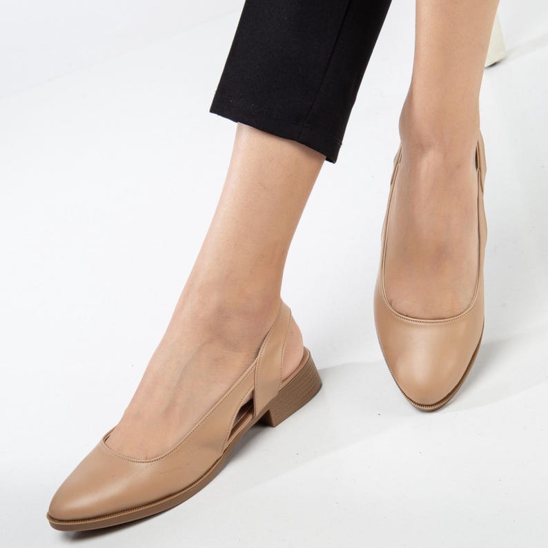 May include: A pair of beige leather heeled slingback shoes with a pointed toe. The shoes have a cut-out design on the side.