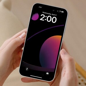 May include: A smartphone with a black background and a colorful abstract design. The time is 2:00 and the date is Wednesday, April 2. The phone is being held in a person's hands.