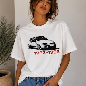 Può includere: T-shirt bianco con grafica di auto in bianco e nero e la scritta rossa "1992-1995". La maglietta ha girocollo e maniche corte. La grafica dell'auto è un'illustrazione dettagliata di un modello hatchback.