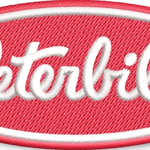 Puede incluir: Un parche ovalado rojo con un contorno blanco y la palabra "Peterbilt" en letras blancas cursivas.