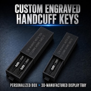 May include: Two black rectangular boxes containing custom engraved handcuff keys. The boxes feature the text "I'M ALWAYS WITH YOU ♡ COME HOME SAFE ♡" on the lids. The keys are black with "SOPO" and "DNIG" engraved in white lettering.