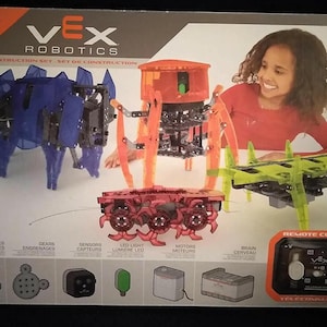 May include: VEX Robotics 4-in-1 robotic kit for ages 8+. The box features images of the assembled robots in blue, orange, and green. Includes remote control and various components like gears, sensors, and LED lights.