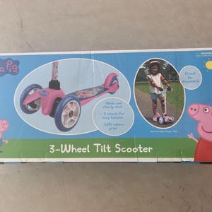 May include: A pink and blue Peppa Pig 3-wheel tilt scooter with soft rubber grips. The box features a cartoon image of Peppa Pig and the text "3-Wheel Tilt Scooter".