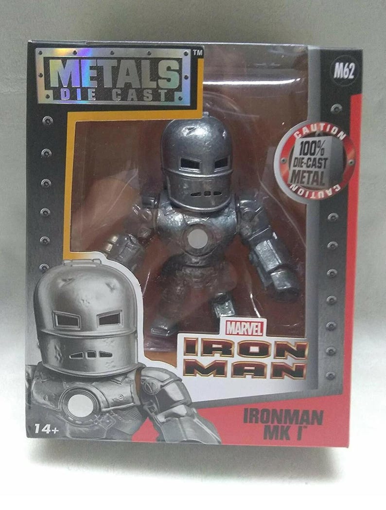 May include: A die-cast metal Iron Man figure in a box. The figure is silver and has a classic helmet design. The box features the Marvel Iron Man logo and the text "METALS DIE CAST". The packaging also includes the text "100% DIE-CAST METAL".