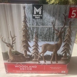 May include: A set of five woodland decorations, featuring two deer and three trees. The deer are in standing and reclining poses. The trees are stylized with a star on top. The box is labelled "Woodland Decor."