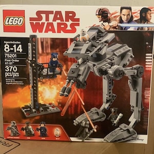 May include: A LEGO Star Wars First Order AT-ST building toy set. The box features images of the AT-ST walker, minifigures, and the Star Wars logo. The set includes 370 pieces and is for ages 8-14.