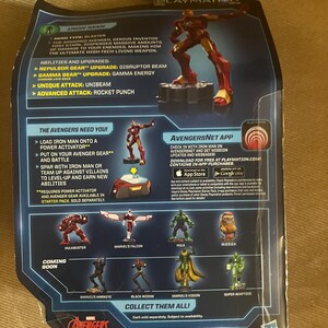 Puede incluir: Parte trasera de un paquete de figuras de acci&oacute;n de Iron Man. El paquete presenta una figura de Iron Man roja y dorada, con texto que describe las habilidades y mejoras del personaje. Tambi&eacute;n se muestran otras figuras de los Vengadores.