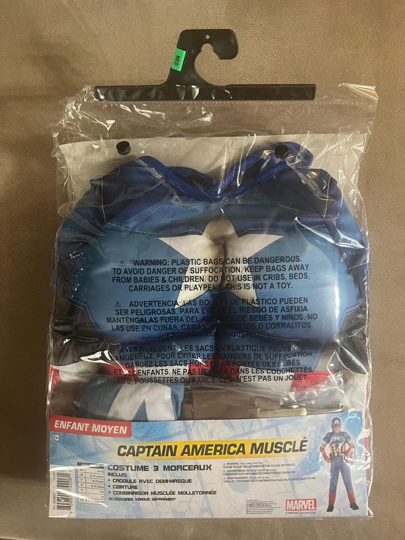 May include: A Captain America muscle costume for children, packaged in a clear plastic bag. The costume includes a mask, belt, and muscle suit. The packaging features the Marvel logo and a graphic of Captain America.