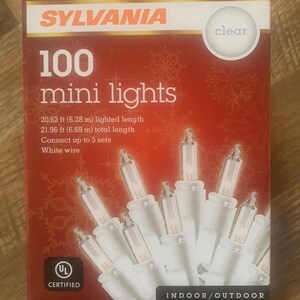 May include: A red box of Sylvania 100 mini lights with clear bulbs and white wire. The box indicates a lighted length of 6.28 m and a total length of 6.69 m. The lights are certified for indoor/outdoor use.