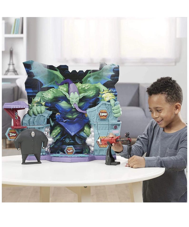 May include: A child plays with a toy playset featuring a large, green monster figure with a purple hat and tongue. The playset includes a figure of a man in a black suit and a red and black toy weapon. The background features a cityscape.
