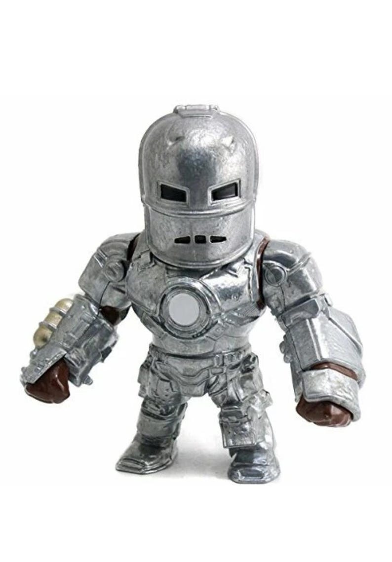 May include: A silver-colored Iron Man action figure. The figure is in a standing pose, with a helmet and armor. The figure has a round white circle on the chest. The figure is a collectible item.