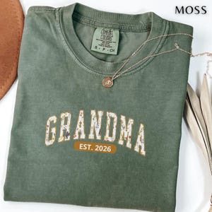 花柄のおばあちゃんコンフォートカラーシャツ、ワイルドフラワーパッチワークのおばあちゃんTシャツ、新米おばあちゃんへのパーソナライズされた2026年設立ギフト、ミミナナシャツギフト