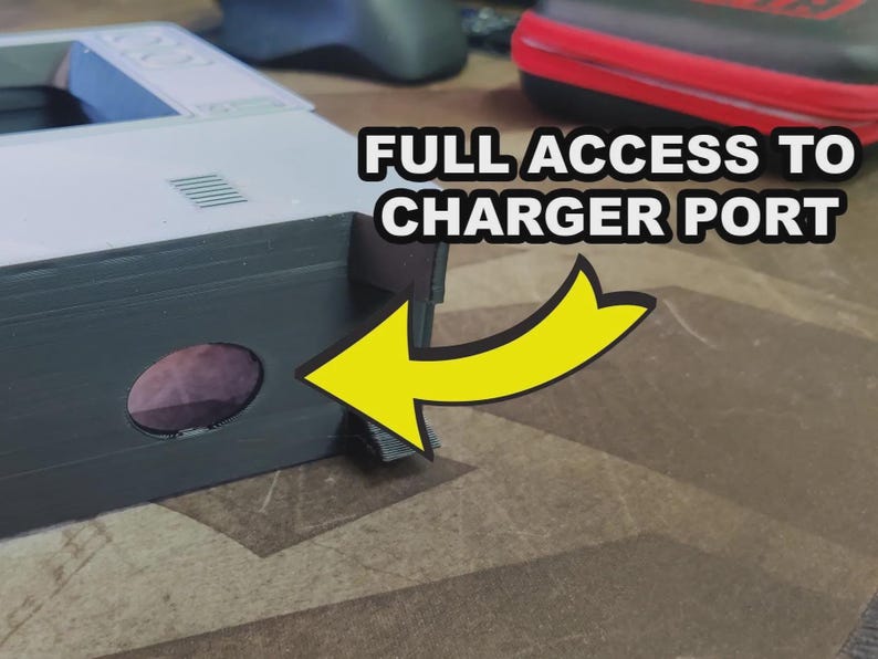Puede incluir: Primer plano de un dispositivo electr&oacute;nico gris y blanco con el texto "FULL ACCESS TO CHARGER PORT" y una flecha amarilla que apunta a una abertura circular. El dispositivo est&aacute; sobre una superficie estampada.