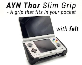 May include: A white handheld gaming console with a black screen and colorful buttons, secured in a black slim grip accessory. The text reads: AYN Thor Slim Grip - A grip that fits in your pocket with felt. The device features a D-pad and dual joysticks.