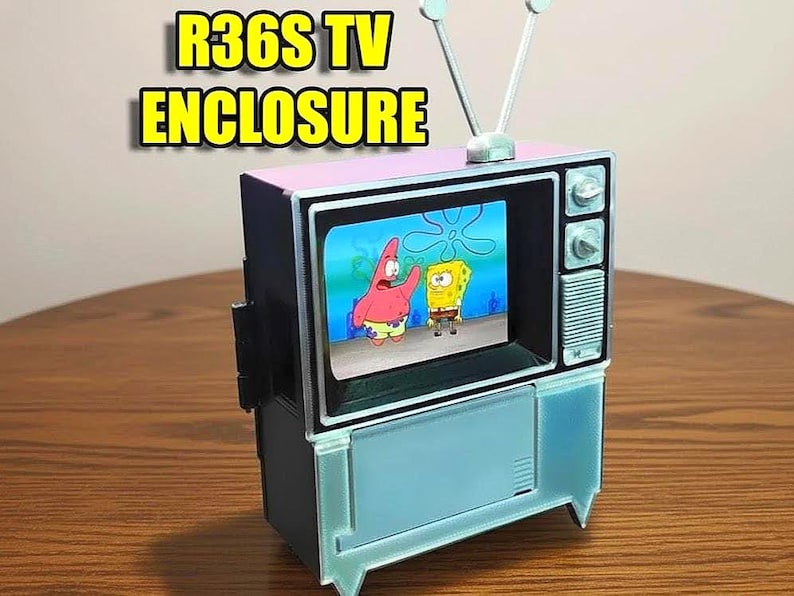 Puede incluir: Un peque&ntilde;o recinto de TV con una pantalla que muestra personajes de Bob Esponja. El recinto es una mezcla de rosa, negro y azul claro, con una antena plateada. El texto "R36S TV ENCLOSURE" se muestra en la parte superior.