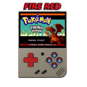 May include: A handheld video game console with a gray and black exterior. The screen displays the title "Pokémon FireRed Version" with a red and orange Charizard. The console has a red directional pad, four gray buttons, and a black start button.